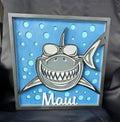 Decorative sign with a shark design and 'Maui' text on a blue background