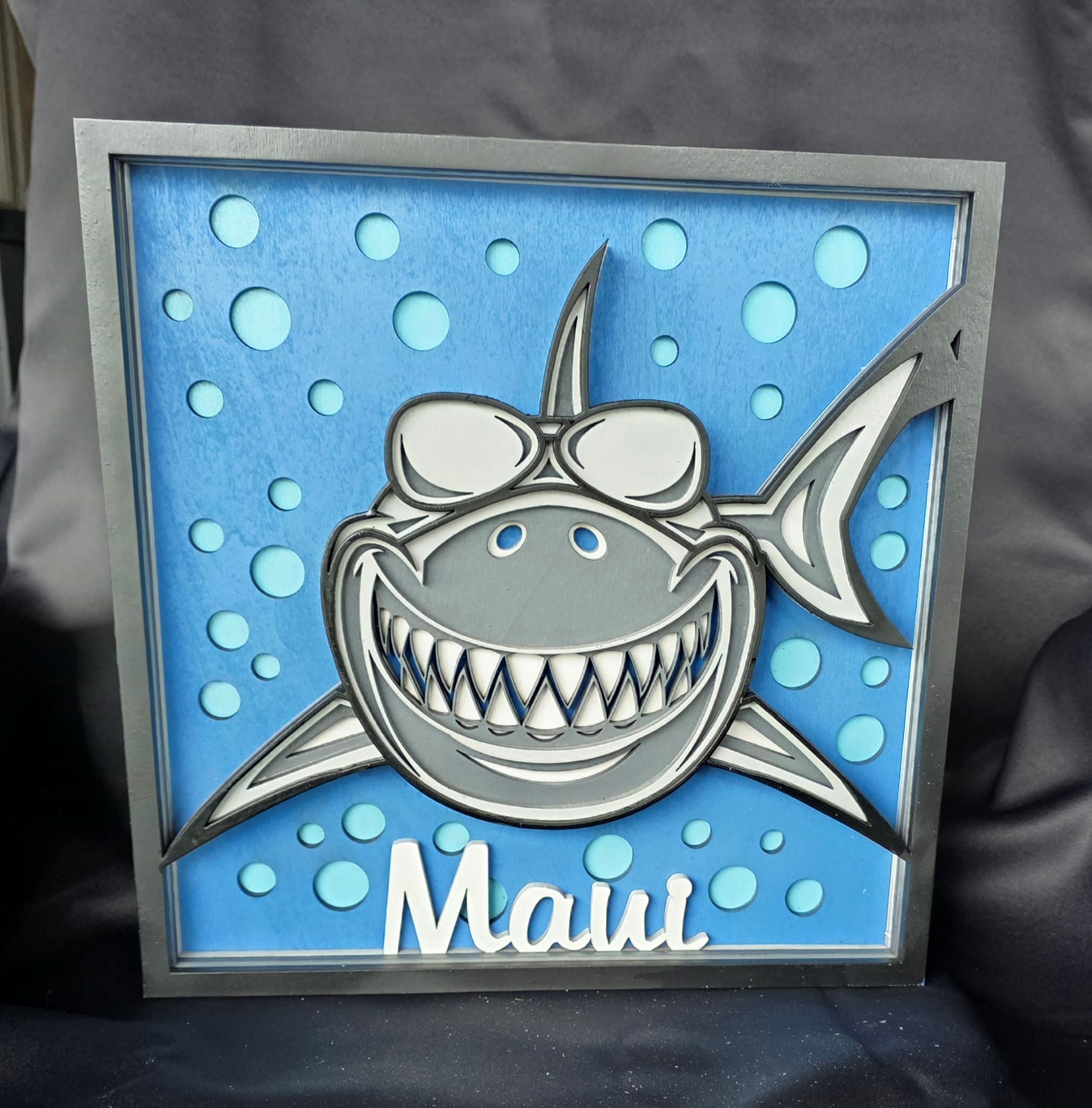 Decorative sign with a shark design and 'Maui' text on a blue background