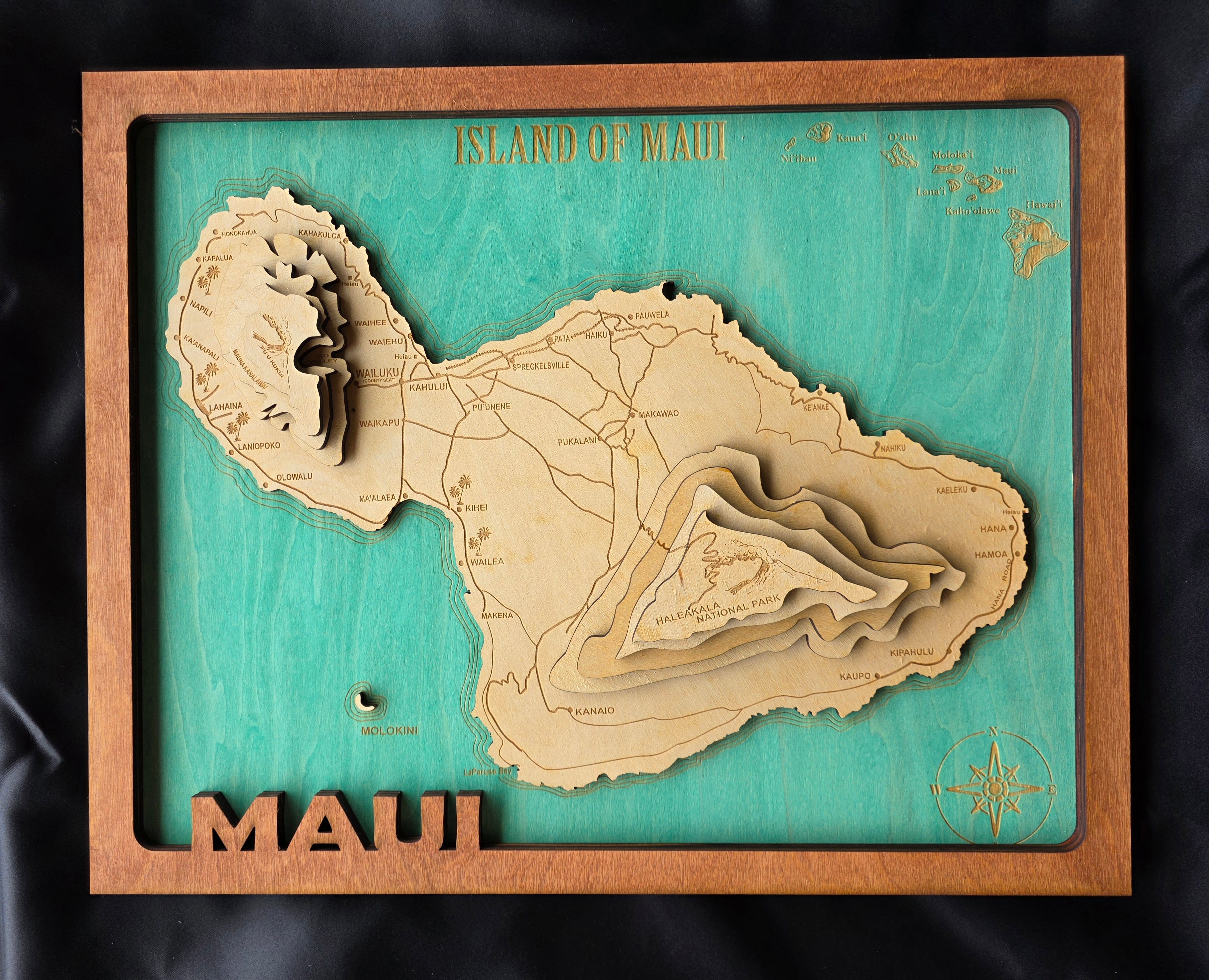 Wooden map of Maui with a teal background