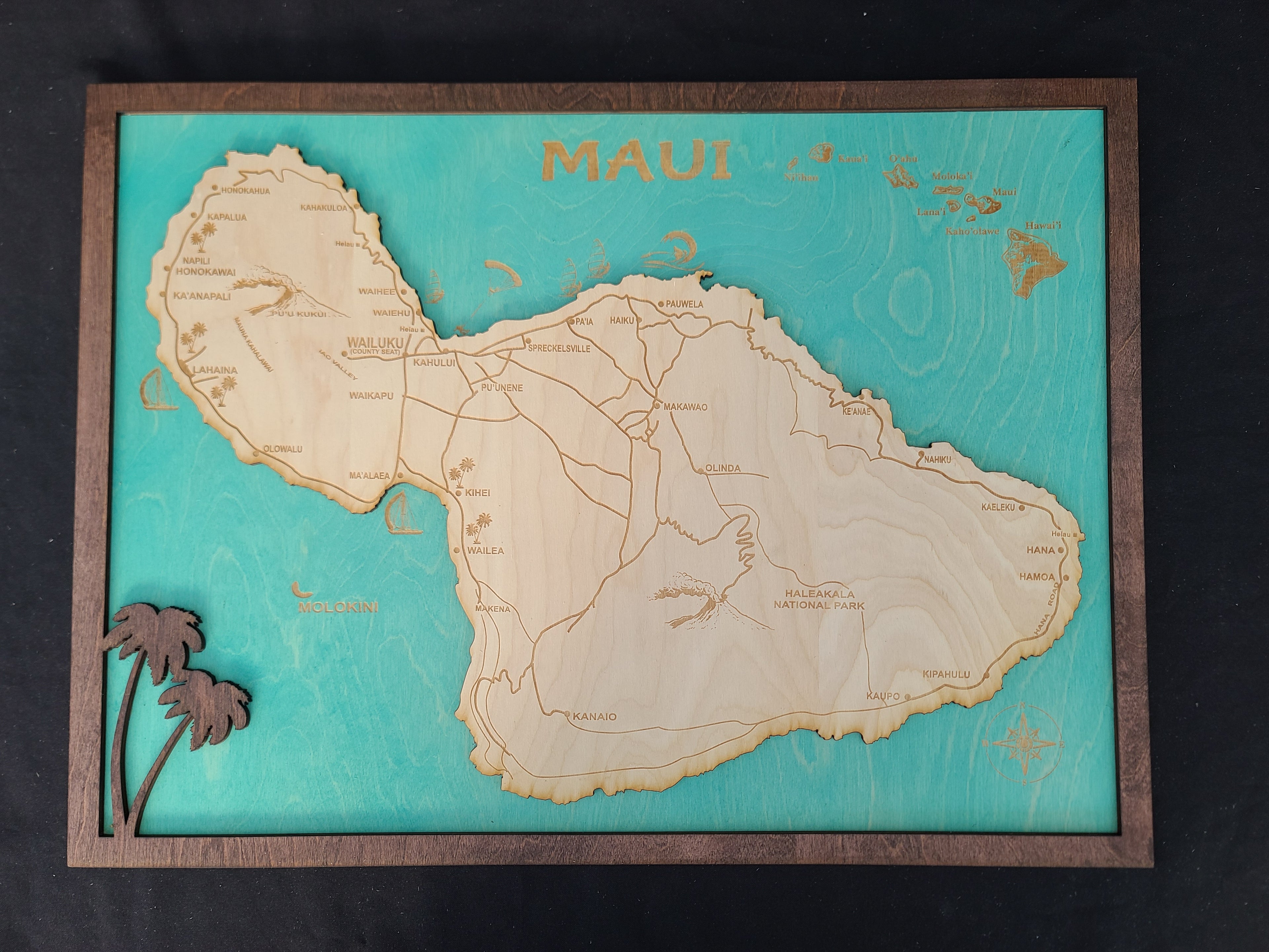 Wooden map of Maui with a teal background and wooden border